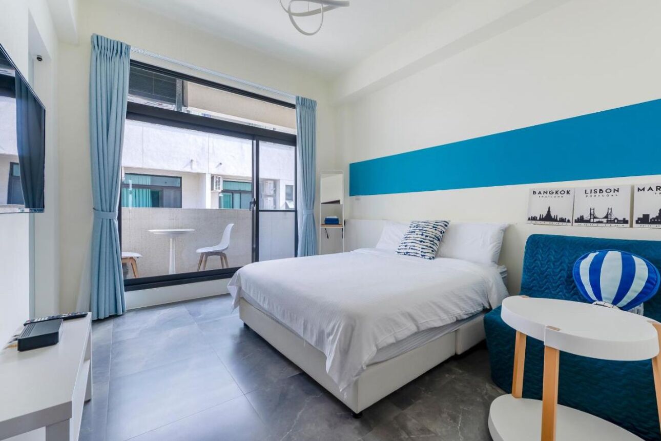 Een moderne hotelkamer met een groot bed, een tafeltje en uitzicht op het balkon.
