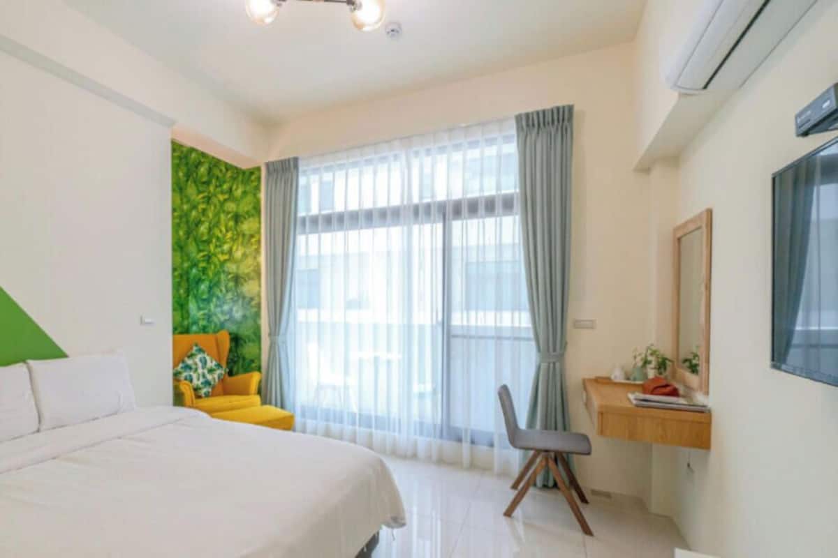 A bedroom with a bed, a desk, and a chair.