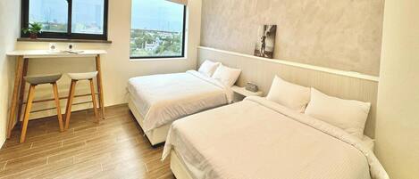 A hotel room with two beds, a desk with a chair, a window with a view, and an air conditioning unit.