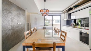 A modern kitchen with a large island, white cabinets, and stainless steel appliances. - Miguo Homestay (Wujie)
