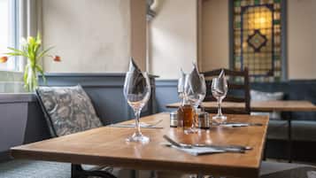 Una mesa de comedor con tres copas de vino, una botella y cubiertos.