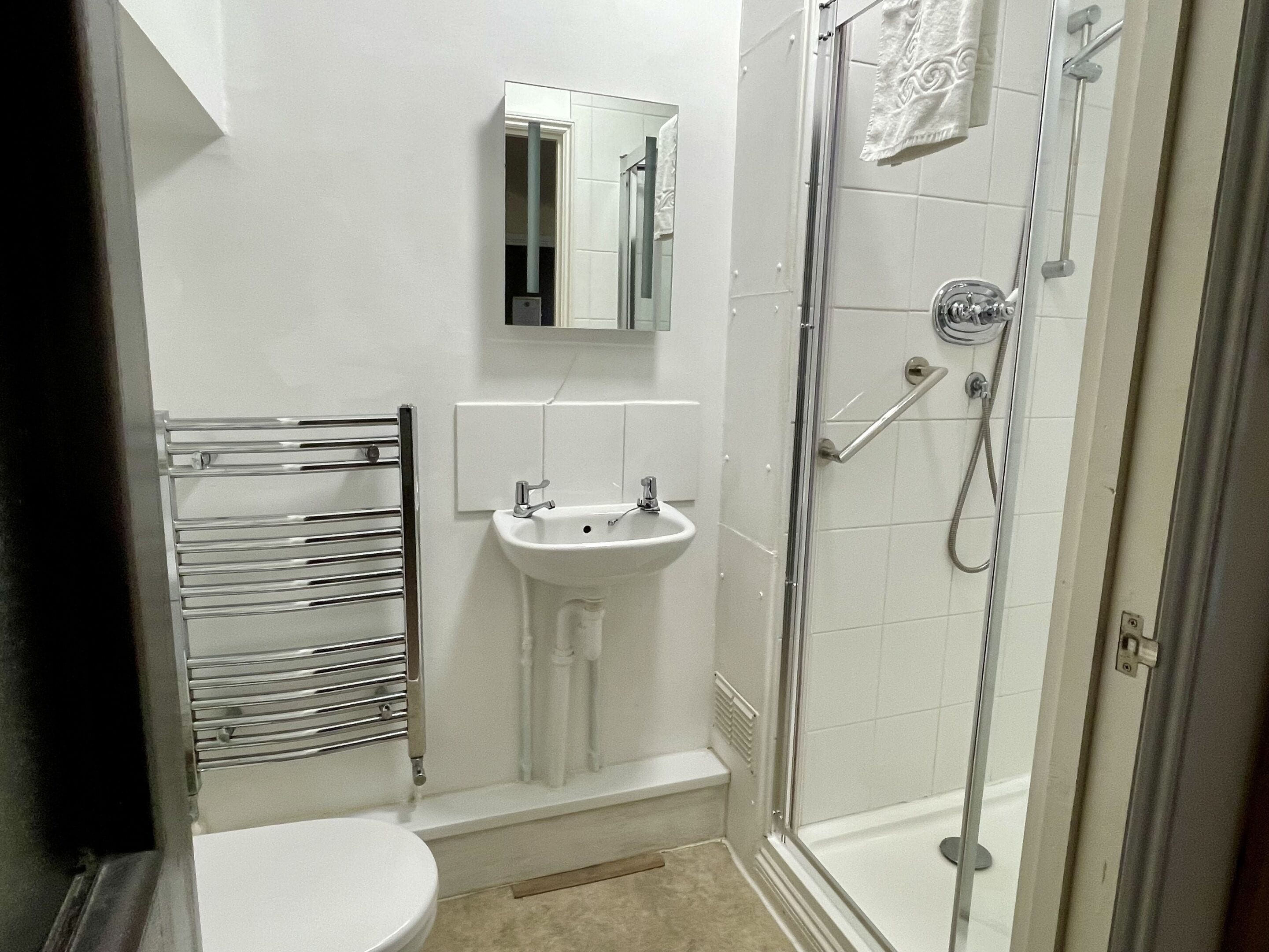 Un baño con inodoro, lavamanos y ducha con mampara de vidrio.