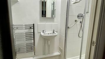 Un baño con inodoro, lavamanos y ducha con mampara de vidrio.