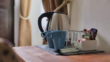 Ett träbord med en kaffebryggare, två blå muggar, en glasburk och en behållare med pennor och andra kontorsartiklar.