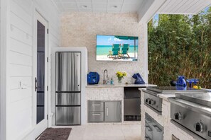 A modern kitchen with stainless steel appliances, a flat-screen TV, and a view of the ocean.