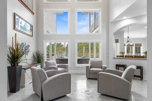 A spacious living room with large windows, a modern fireplace, and comfortable seating.