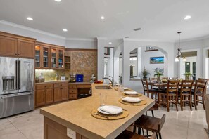 A modern kitchen with a central island, wooden cabinets, and stainless steel appliances.