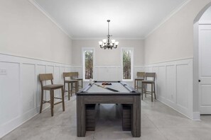 A pool table in a room with white walls and wooden paneling, surrounded by four chairs. - Luxe, Lakefront, Heated Pool/Spa, 5 mins to Beach (Santa Rosa Beach)