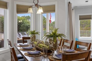 A dining area with a wooden table set for four, surrounded by chairs. There are decorative vases and a bowl of fruit on the table. - Luxe, Lakefront, Heated Pool/Spa, 5 mins to Beach (Santa Rosa Beach)