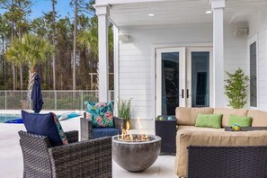 An outdoor patio with wicker furniture, a fire pit, and a pool. - Luxe, Lakefront, Heated Pool/Spa, 5 mins to Beach (Santa Rosa Beach)