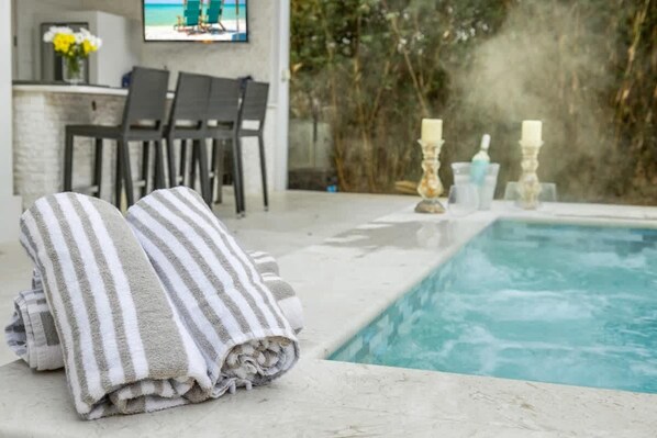 A pool area with towels, a table with candles, and chairs.