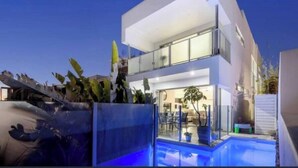 A modern two-story house with a swimming pool, large windows, and a balcony. - Waterfront at Serenity (Maroochydore)
