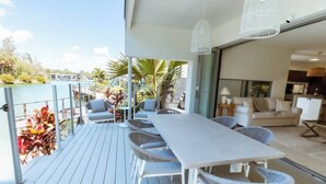 A balcony with a dining table and chairs, a sofa, and a kitchen area. - Waterfront at Serenity (Maroochydore)