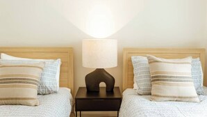 A double bed with a striped pillow and a bedside table with a lamp. - Waterfront at Serenity (Maroochydore)