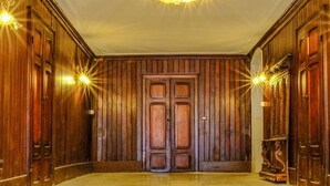 Un pasillo con paneles de madera, un candelabro y un conjunto de puertas dobles.