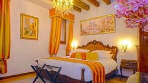 Una habitación de hotel con una cama grande, una araña y obras de arte en las paredes.