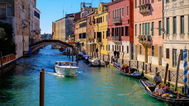 Un canal en Venecia con góndolas, un puente y edificios coloridos.