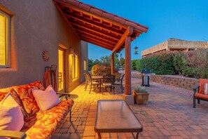 Eine Außenpatio mit einer Couch, einem Tisch, Stühlen, einer Pergola und einem Grill.