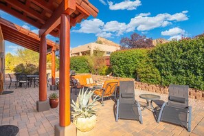 Eine Terrasse im Freien mit Holz-Pergola, Gartenmöbeln und einem großen Topfpflanzen.