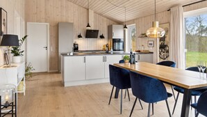 Eine moderne Küche mit Holzvertäfelung, einer Kochinsel in der Mitte und Pendelleuchten.