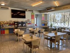 A modern cafe with a counter, seating area, and large windows. - Hotel Liberty Self Check-in (Bellinzona)
