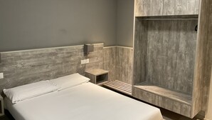 A modern bedroom with a large bed, a wooden wardrobe, and a small bedside table. - Hotel Liberty Self Check-in (Bellinzona)