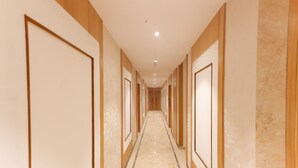 A long, narrow hallway with wooden paneling and a marble floor, leading to a series of doors. - Hotel Sarc Inn (Varanasi)