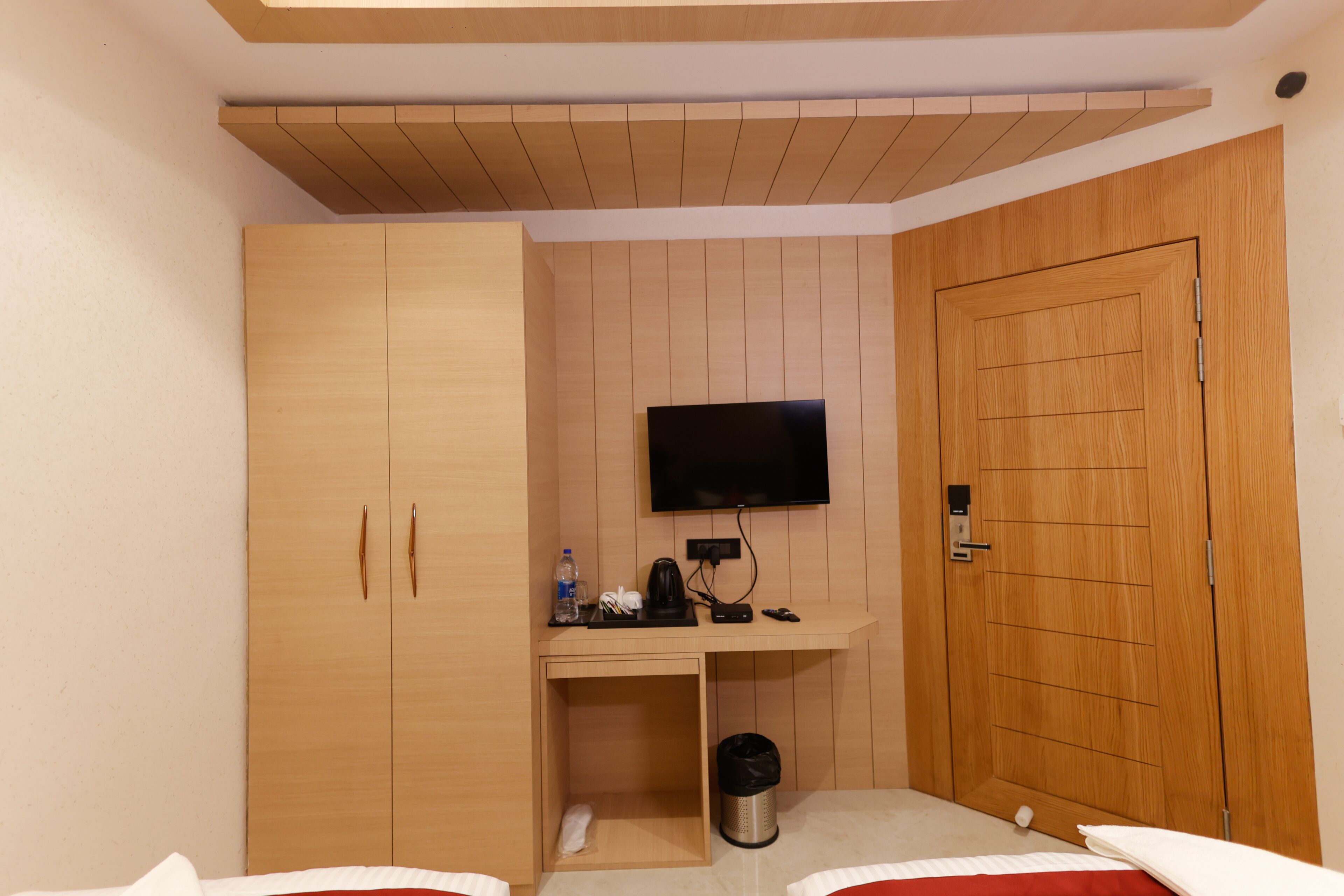 Een hotelkamer met een houten kledingkast, een bureau met een televisie en een bed.