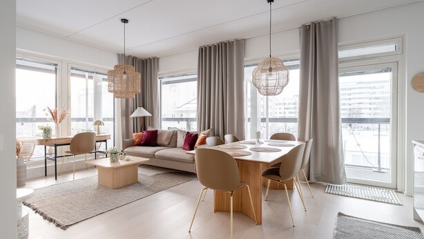 Un salon moderne avec un canapé, une table à manger, des chaises et de grandes fenêtres.