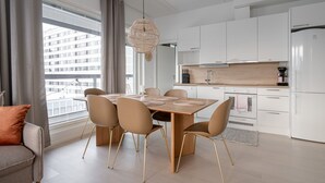 Une cuisine moderne avec des meubles blancs, un plan de travail en bois et un coin repas comprenant une table et des chaises.