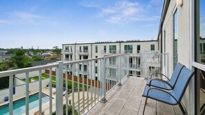 En balkon med swimmingpool, stol og udsigt over bybilledet.