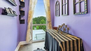 Una habitación con paredes moradas, una mesa con mantel a rayas y una ventana con cortinas.