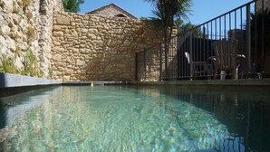 A clear pool with stone walls and metal fencing. - Gites la Remise (PUIMISSON)