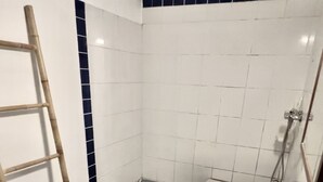 Une salle de bain avec un lavabo blanc, un miroir, une douche et une échelle en bois.