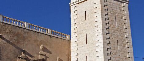 A tall stone tower with a clock, a door with inscriptions, and a balcony.