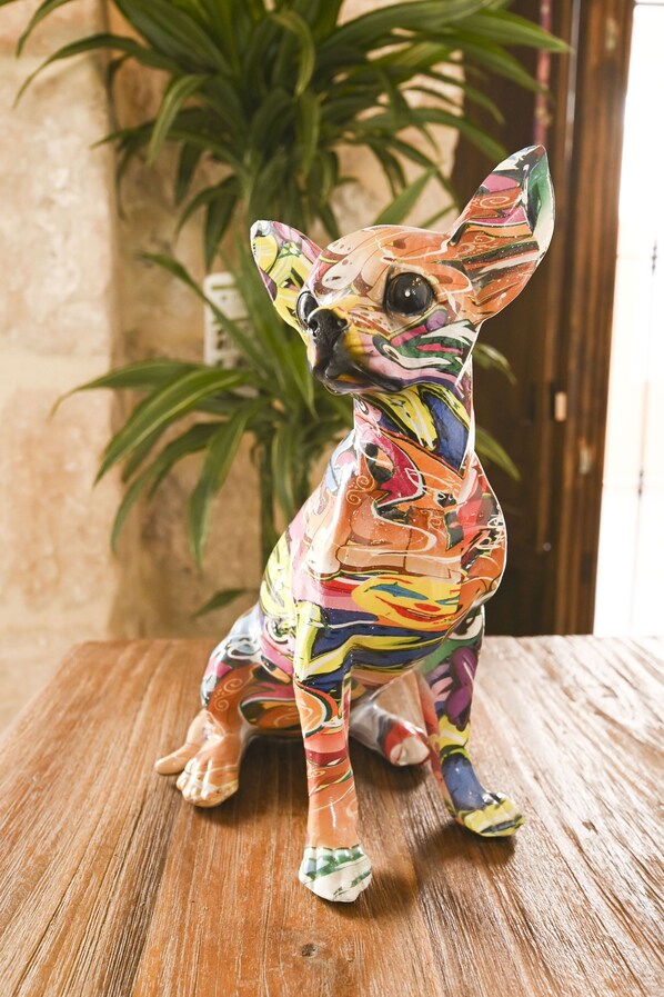 Una figurita de perro de cerámica, de colores, sobre una superficie de madera.