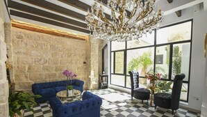 A room with a checkered floor, a stone wall, a chandelier, and large windows. - Ca sana Boutique Taulada Moraira (Teulada)