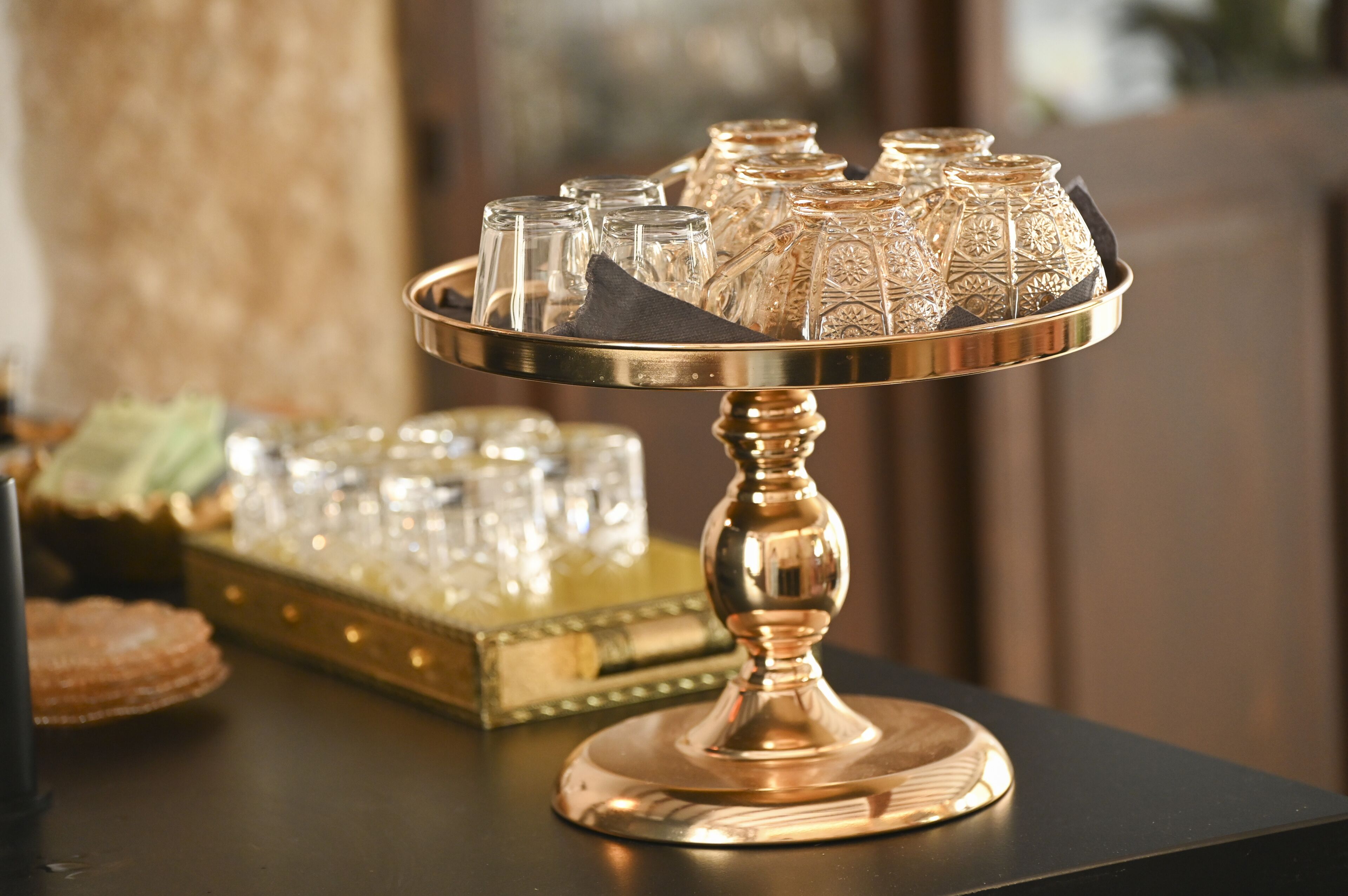 Uma bandeja com copos de vidro decorados e um suporte ornamental.