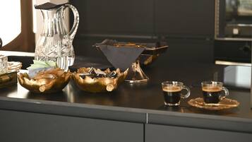 A bar area with a coffee machine, two cups of coffee, a glass pitcher, and decorative bowls.