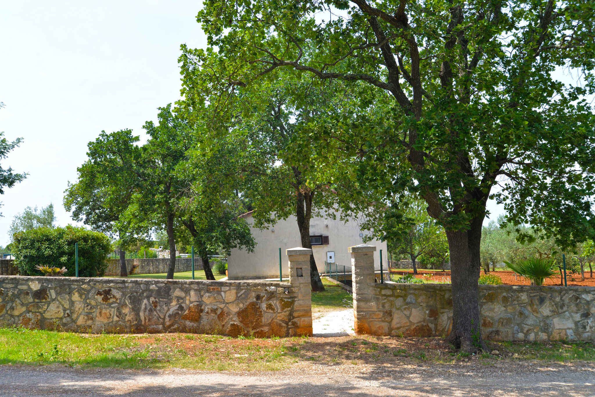 A stone wall with a gate leading to a building surrounded by trees.