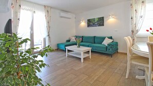 A living room with a teal sofa, a white coffee table, and a dining table with chairs. - Villa stylishly furnished with swimming pool (Bale)