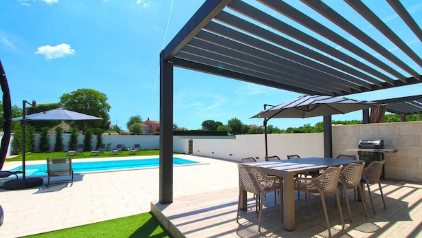 An outdoor patio with a pool, a covered dining area, and a barbecue grill. - Villa stylishly furnished with swimming pool (Bale)