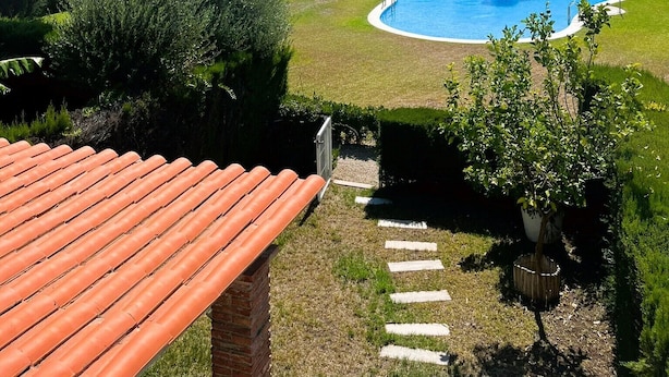 A residential area with a swimming pool surrounded by well-maintained lawns and trees. - Villa Conchi (Les Tres Cales)