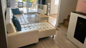 A modern living room with a white sofa, a small table, a TV, and a fireplace. - Villa Conchi (Les Tres Cales)