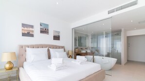 A modern hotel room with a large bed, a glass shower enclosure, and a view of the sea. - Villa Aurum (Zadar)