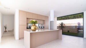 A modern kitchen with a central island, built-in appliances, and a large window offering a view of the outdoors. - Villa Aurum (Zadar)