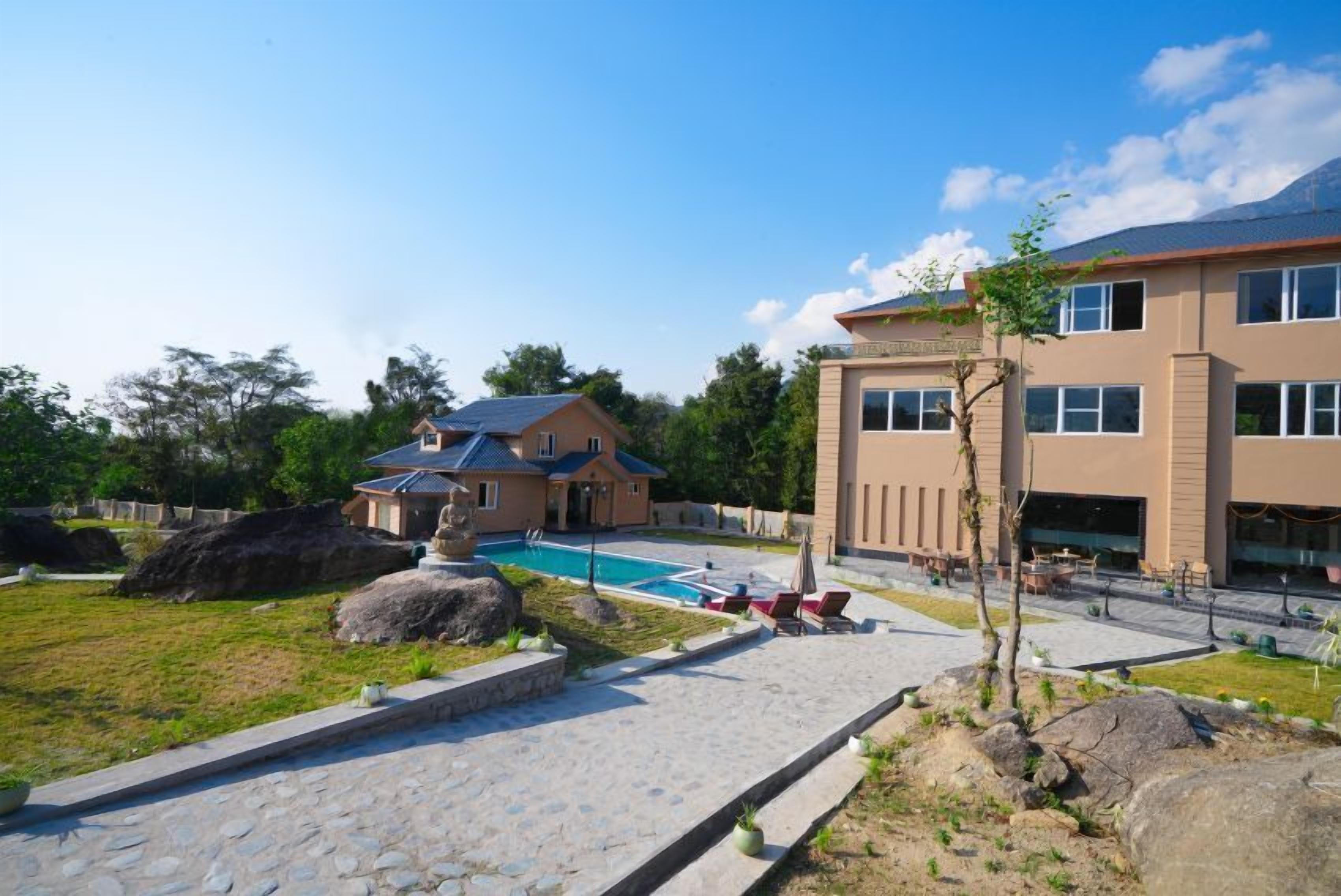A modern hotel with a swimming pool, outdoor seating, and a well-maintained garden.