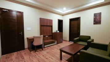 A room with a wooden floor, a desk, a chair, a sofa, and a cabinet.