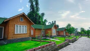 A row of wooden cabins with green roofs, surrounded by well-maintained grass and stone pathways.