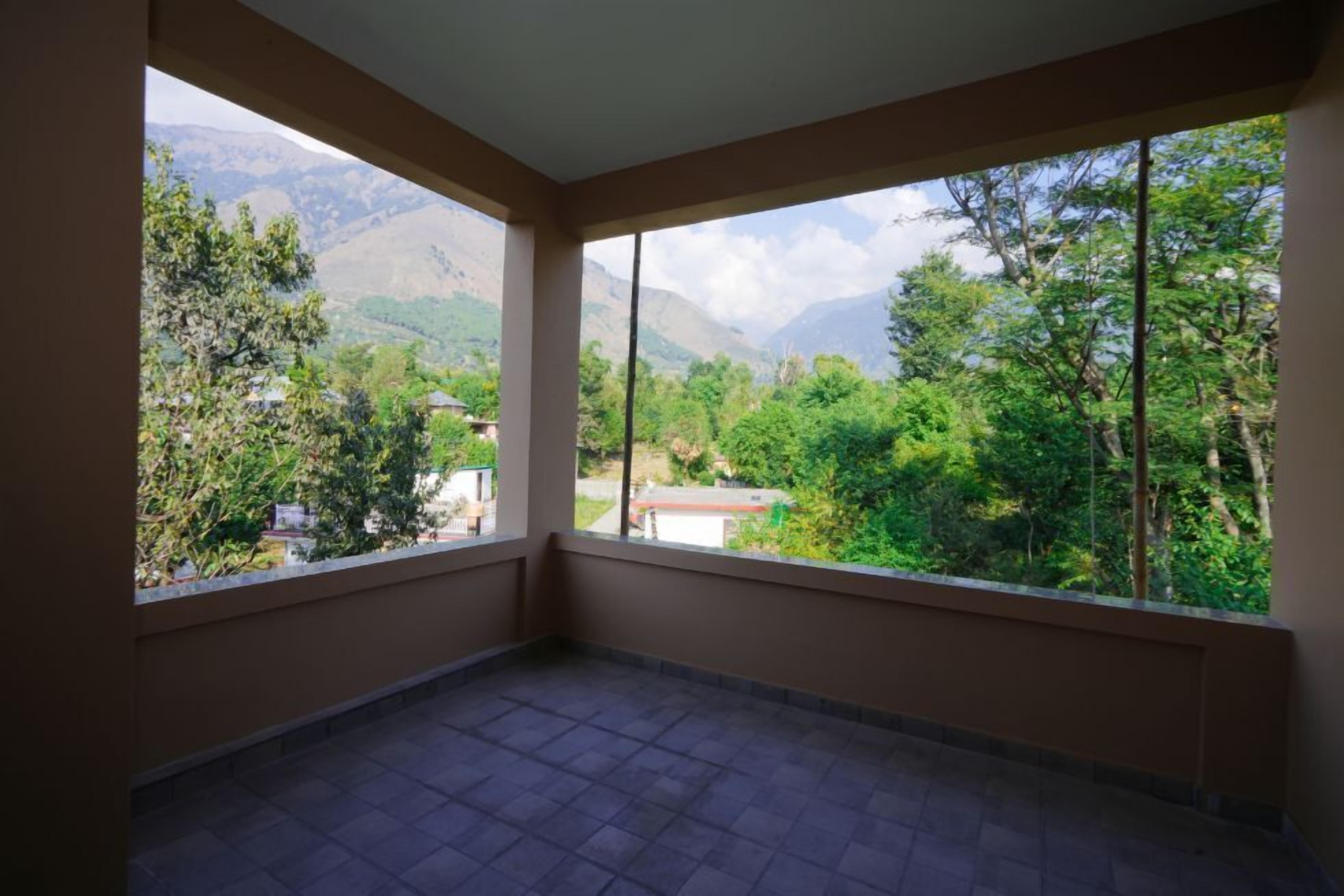 Un balcón con vistas a montañas y vegetación.